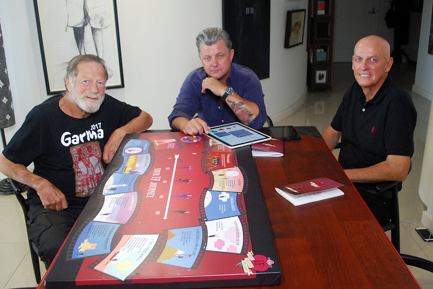 Actor Jack Thompson, IF Project founder Clinton Hoffmann and life coach Barry Hogg sit at a table with a copy of IF poem.