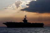 The US naval vessel USS Theodore Roosevelt in front of a sunset.