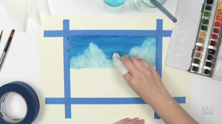 Hand uses fabric on finger to paint picture of clouds