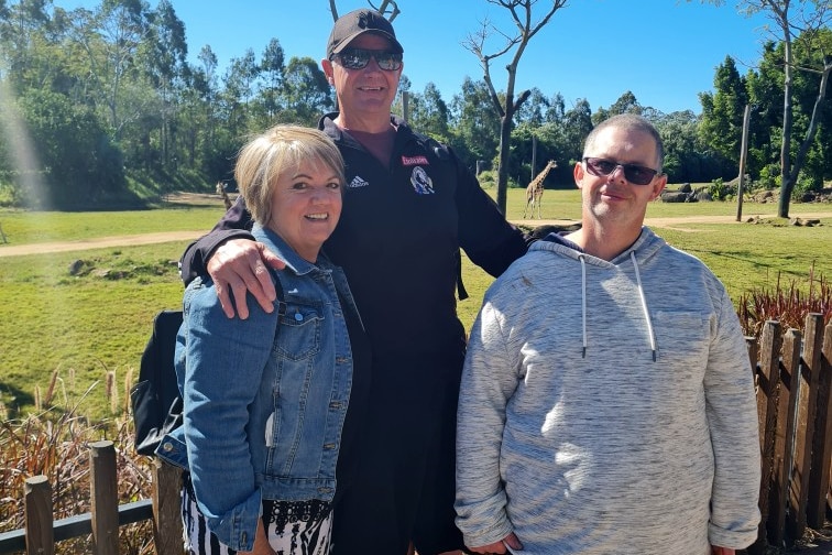 A lady and two men stand together smiling for a photo.