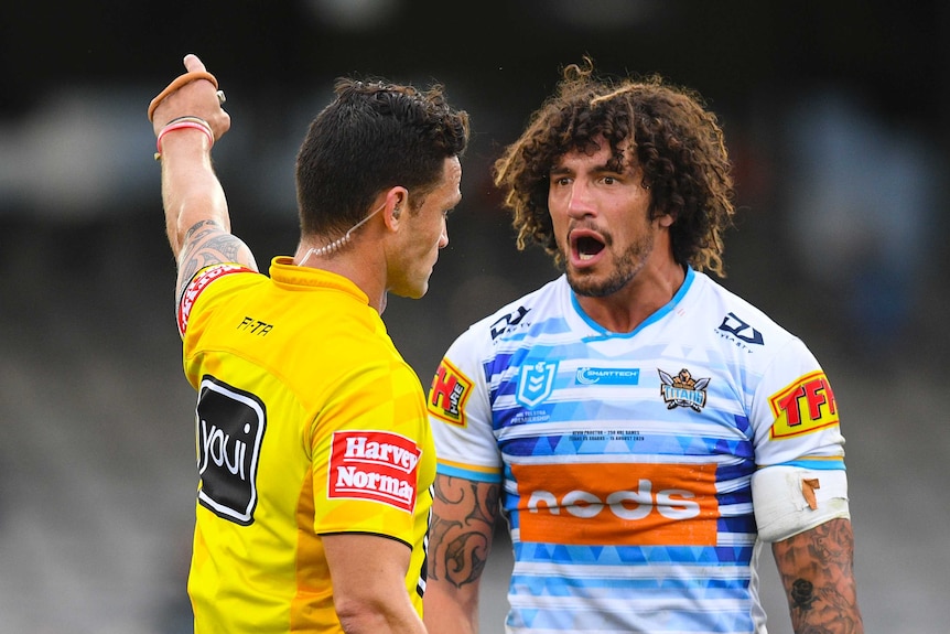 An NRL referee points with the index finger on his left hand as he sends off a Gold Coast Titans player.
