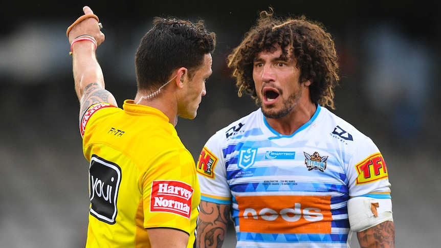 An NRL referee points with the index finger on his left hand as he sends off a Gold Coast Titans player.