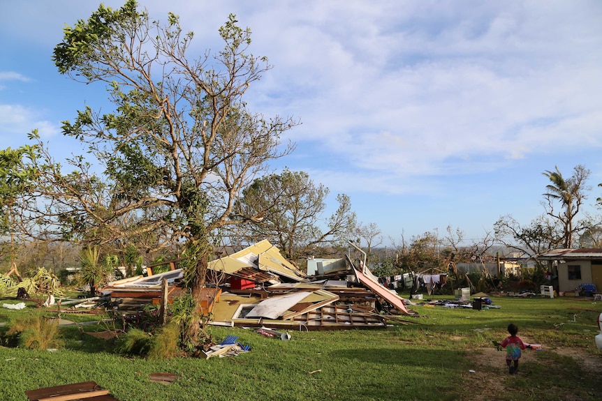 A toddler walks outside damaged homes in Vanuatu