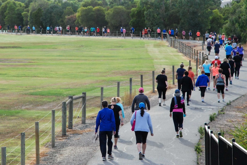 People run and walk on a track around an oval.