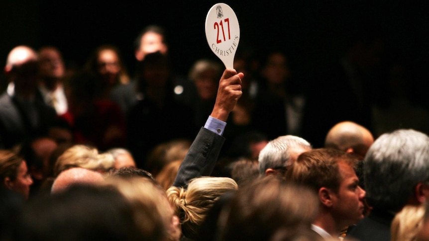 A man holds his hand up while bidding on a work of art inside the auction house Christie's during the Post-War and contemporary Art sale November 15, 2006 in New York City.