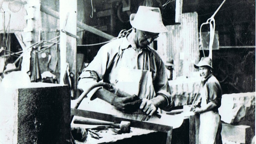 Black and white image of a man in a white hat working. 