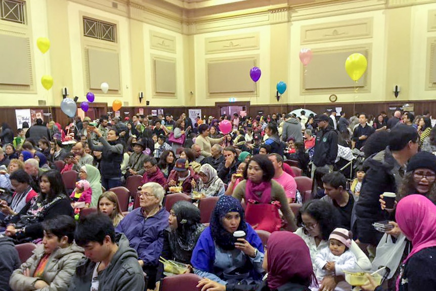 People in seats in a hall, balloons.