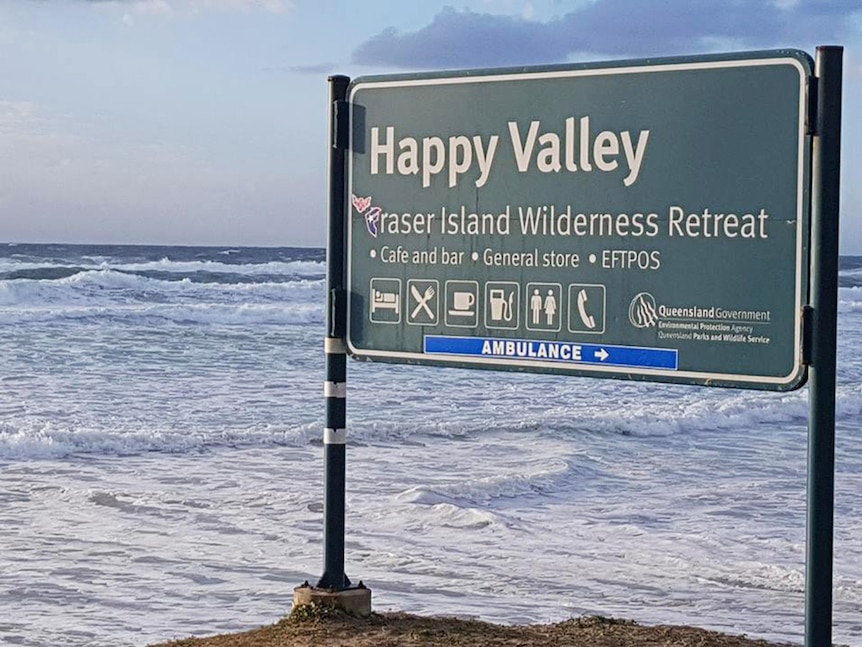 Ocean waves lapping at the foot of a sign on Fraser Island