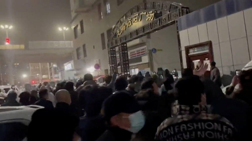 People gather outside town plaza at night.