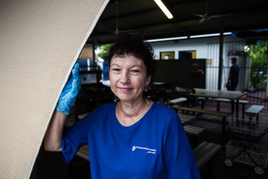 Woman wearing Vinnies skivvies and blue disposable gloves standing under a shade structure.