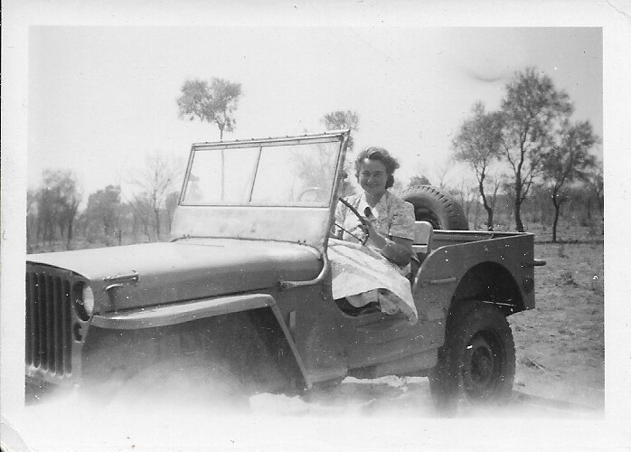 A woman driving a car on an outback station
