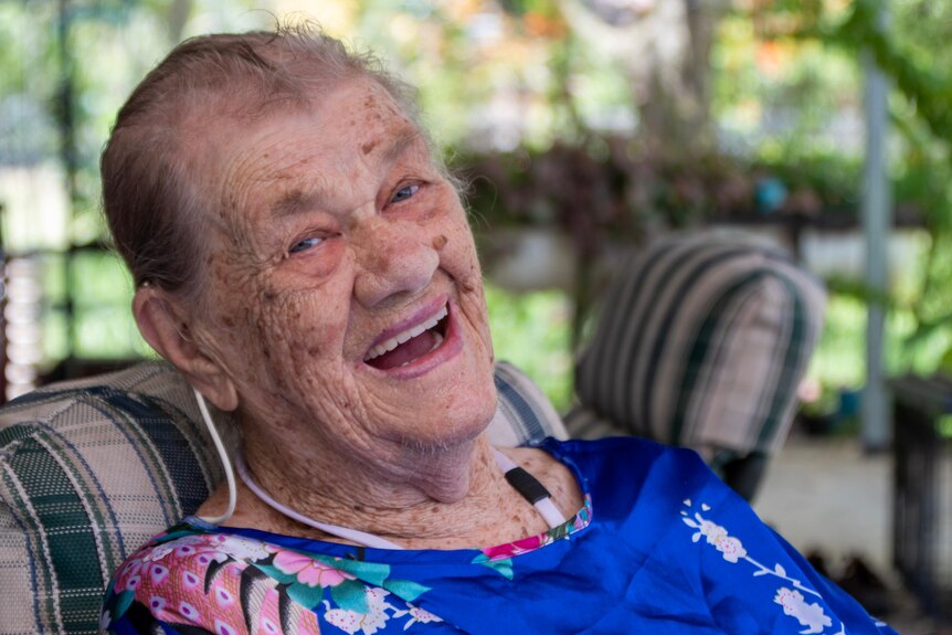 Portrait of an older lady laughing and wearing a colourful blue shirt.
