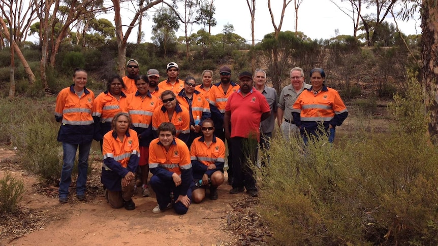 Fifteen indigenous rangers in high visibility clothing stand with course trainers in the bush with Bromus dam in the background