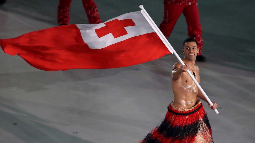 Pita Taufatofua carries the flag of Tonga shirtless