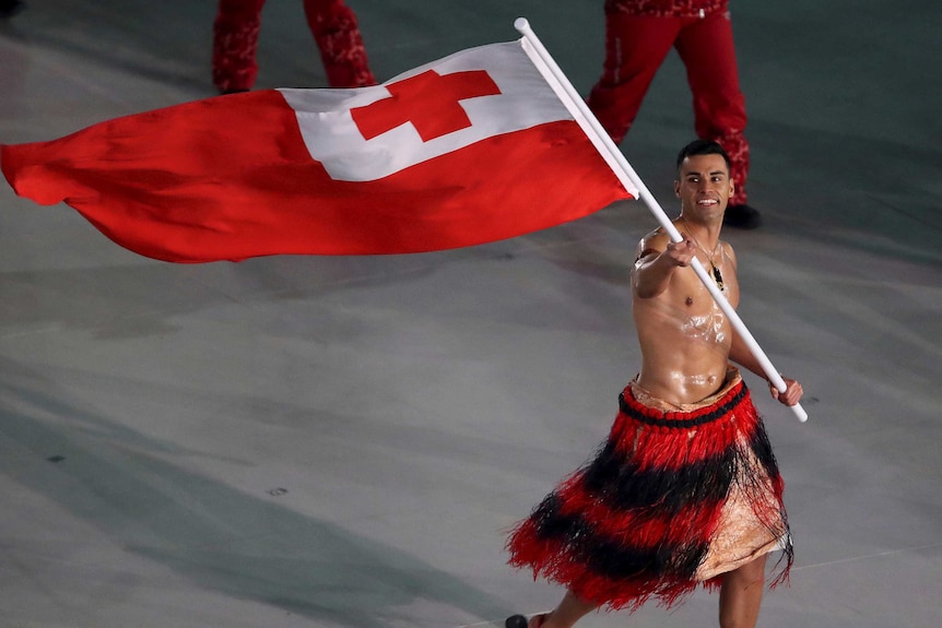 Pita Taufatofua carries the flag of Tonga shirtless