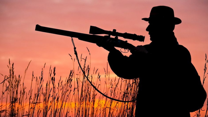 A hunter points a gun.