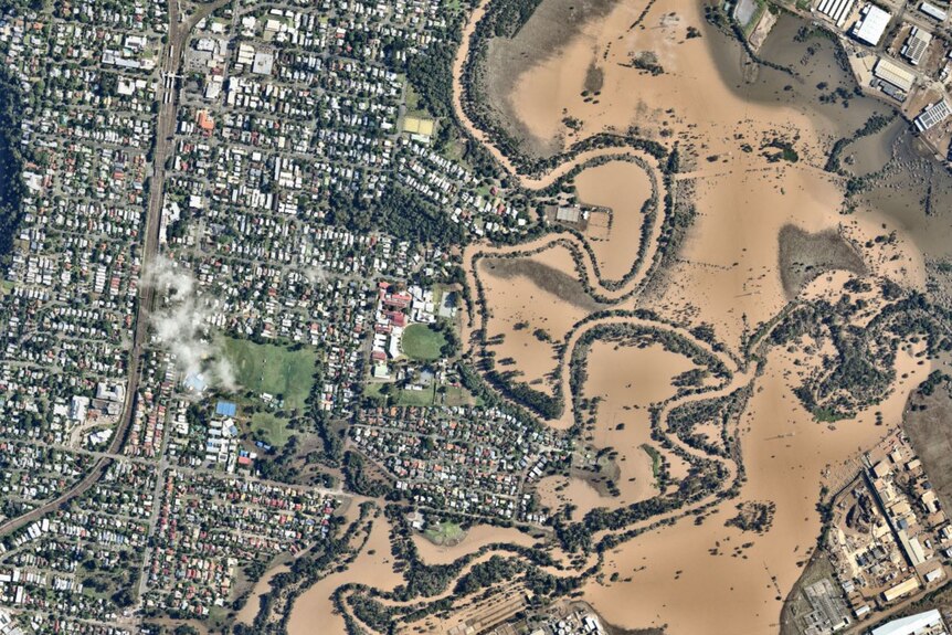 An aerial image provided by Nearmap shows the Brisbane river flooded to the left of the picture.