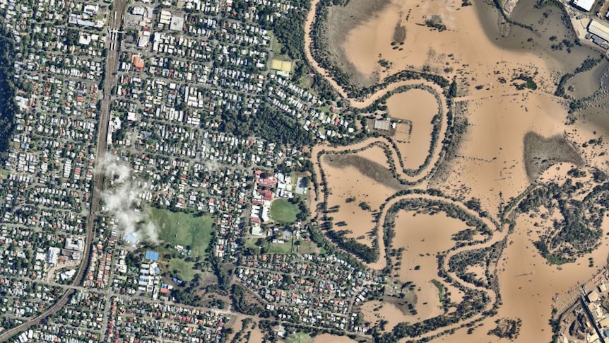 An aerial image provided by Nearmap shows the Brisbane river flooded to the left of the picture.