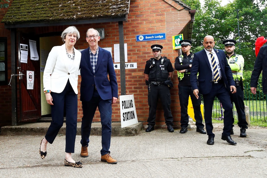 British Prime Minister Theresa May and her husband Philip walk side-by-side as they leave.