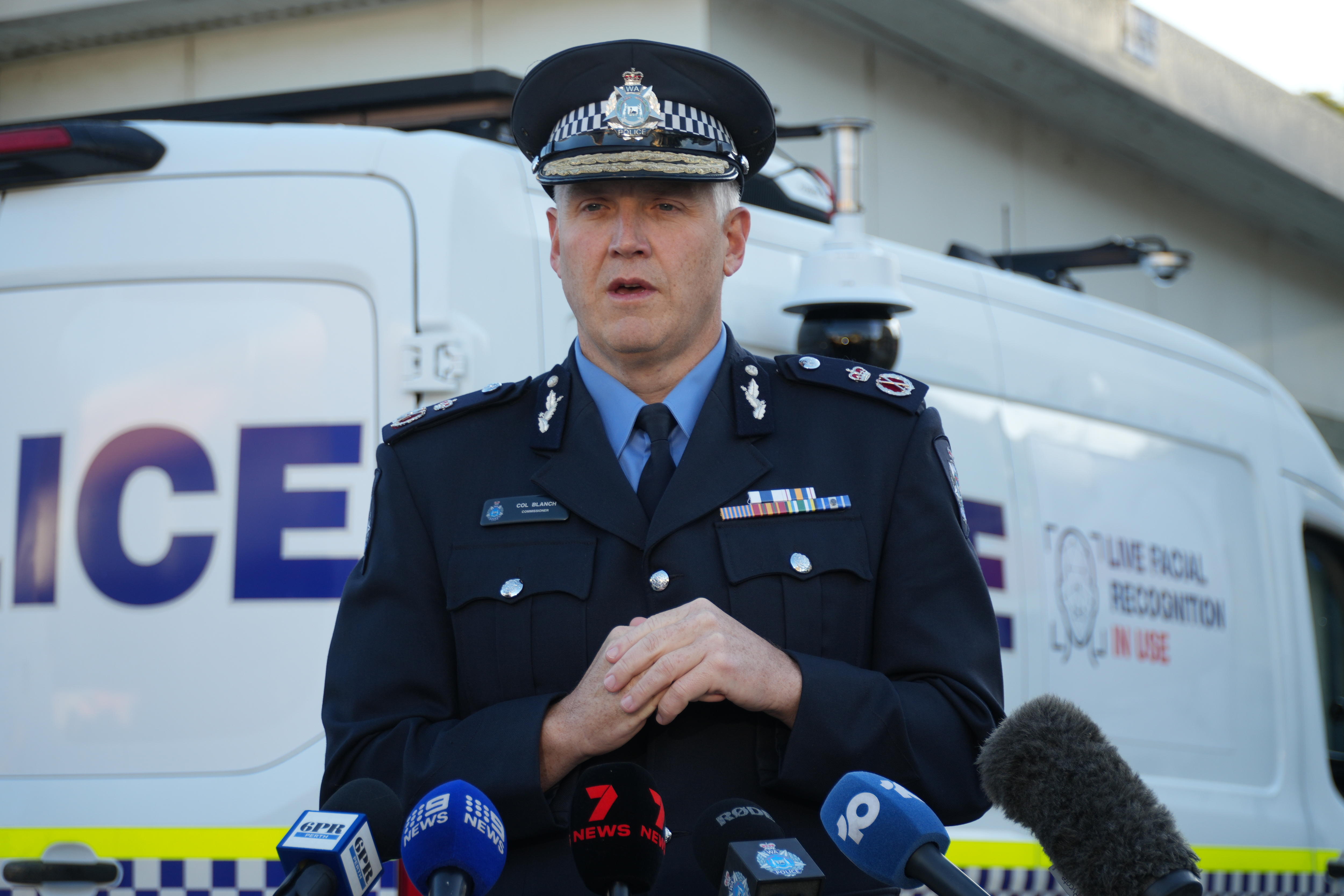Police Commissioner is speaking to the press in front of a surveillance van. 