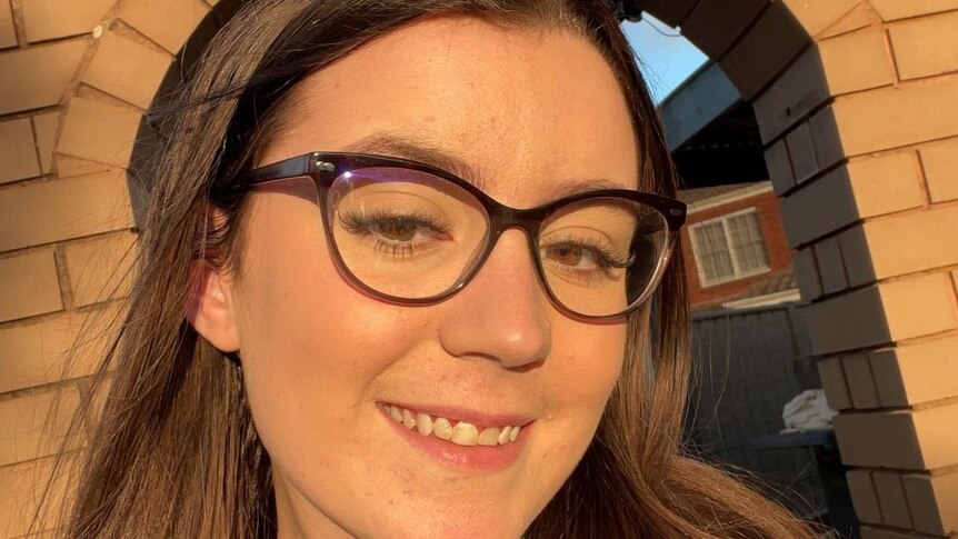 A young woman smiles happily for a selfie.