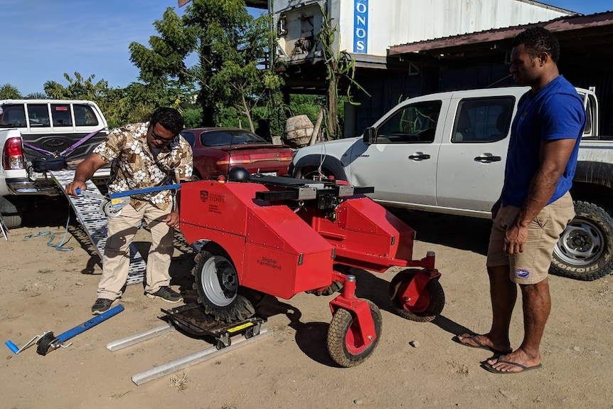 Fijian locals unloading and tinkering with farm robot in Fiji