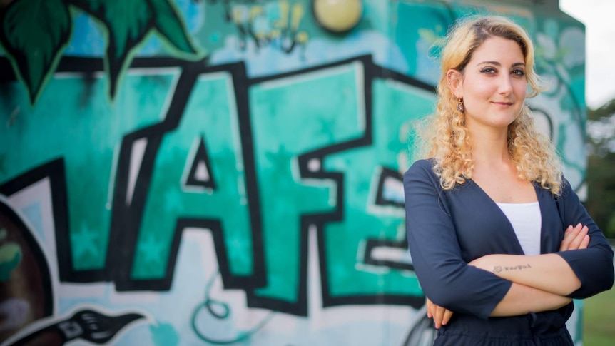 Nada Hassoun stands in front of a graffitied wall at the Tropical North Queensland TAFE campus in Cairns.