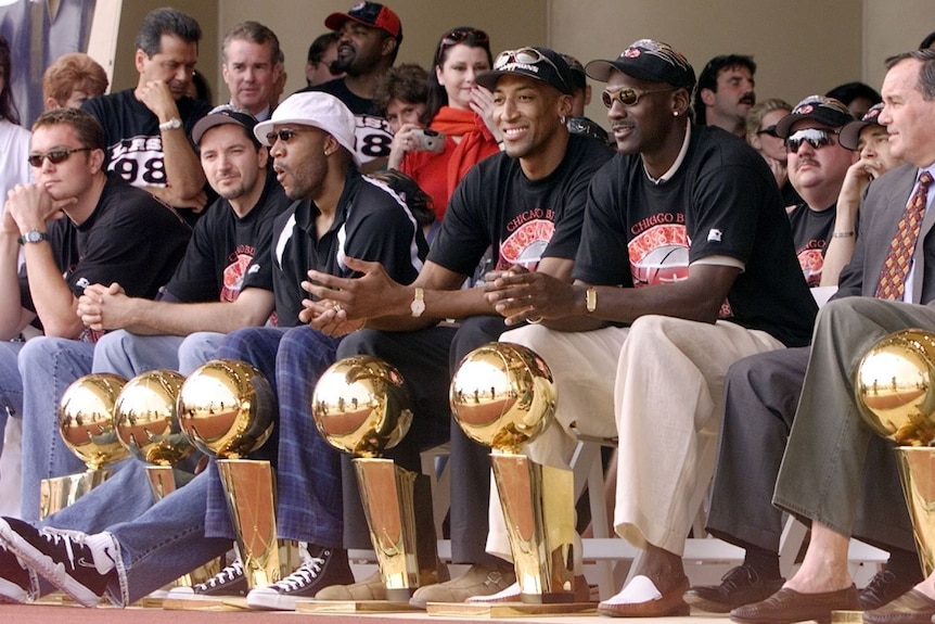 Chicago bulls 1998 winning team sit on stage with championship trophies michael jordan front