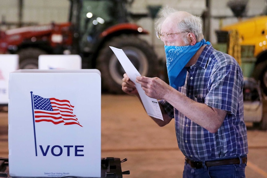 A man with a bandana on his face at a polling station