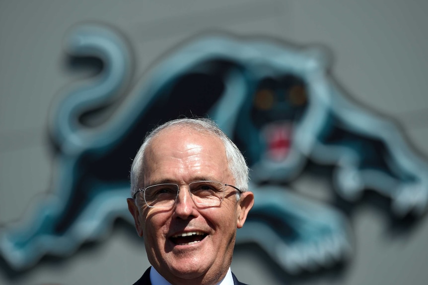 Turnbull laughs in front of a sign of the Panthers mascot