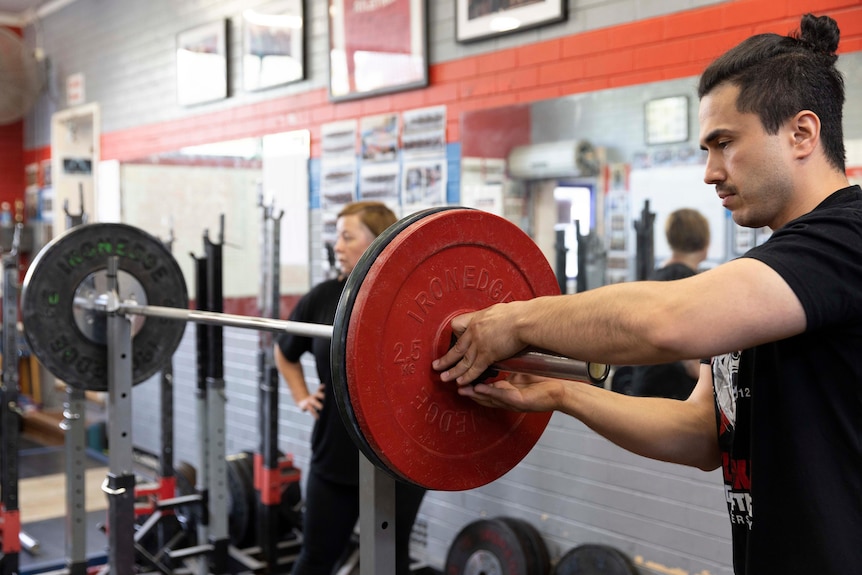 A man adjusts weights on a bar