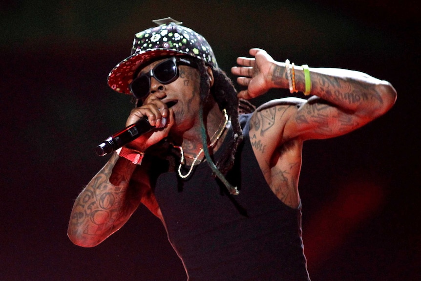 Lil Wayne wears a baseball cap and sunglasses as he performs during a concert