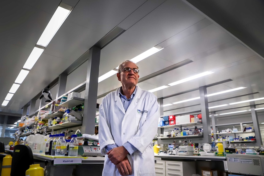 Man with glasses wearing labcoat stands in science laboratory.