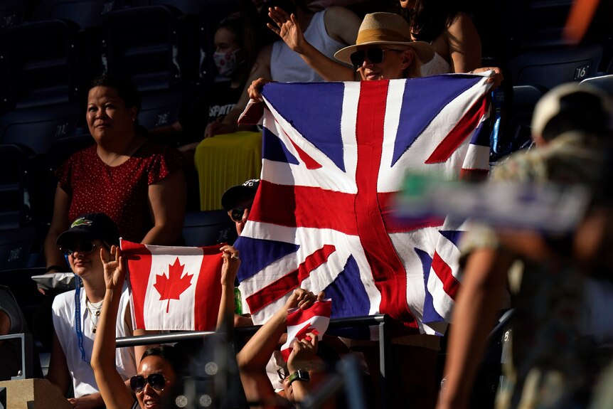The sunlight shines on fans in the stands at Flushing Meadows carrying flags during the US Open women's singles final