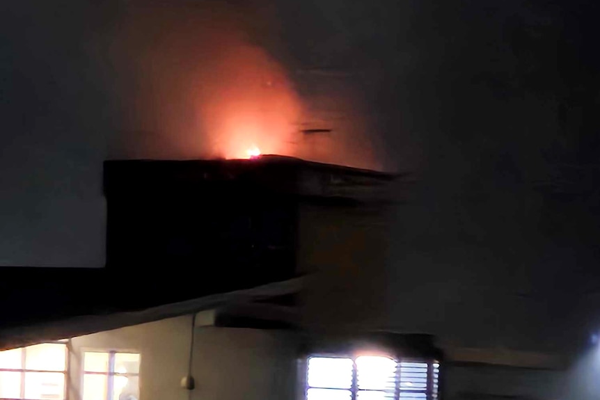 Fire on top of an apartment building at night