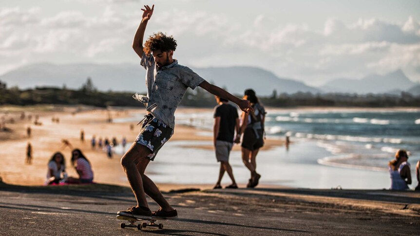 A man balances on a skateboard at the beach