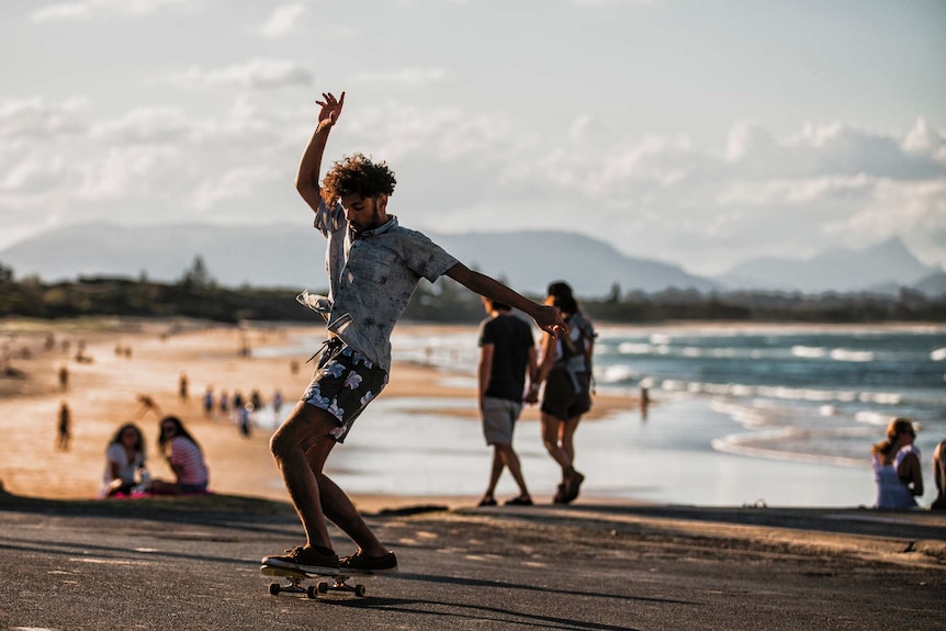 A man balances on a skateboard at the beach