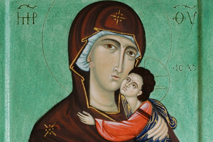 An image of an icon showing the Virgin Mary holding baby Jesus on a green background.