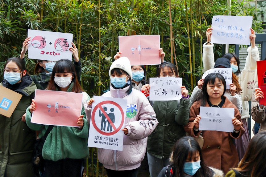 A group of Chinese women in face masks holding up #metoo signs