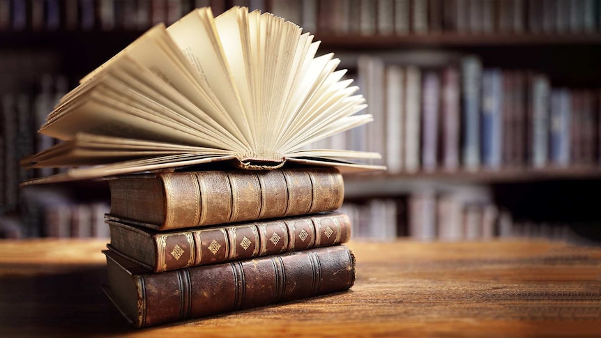 four old books laying on a table in a library