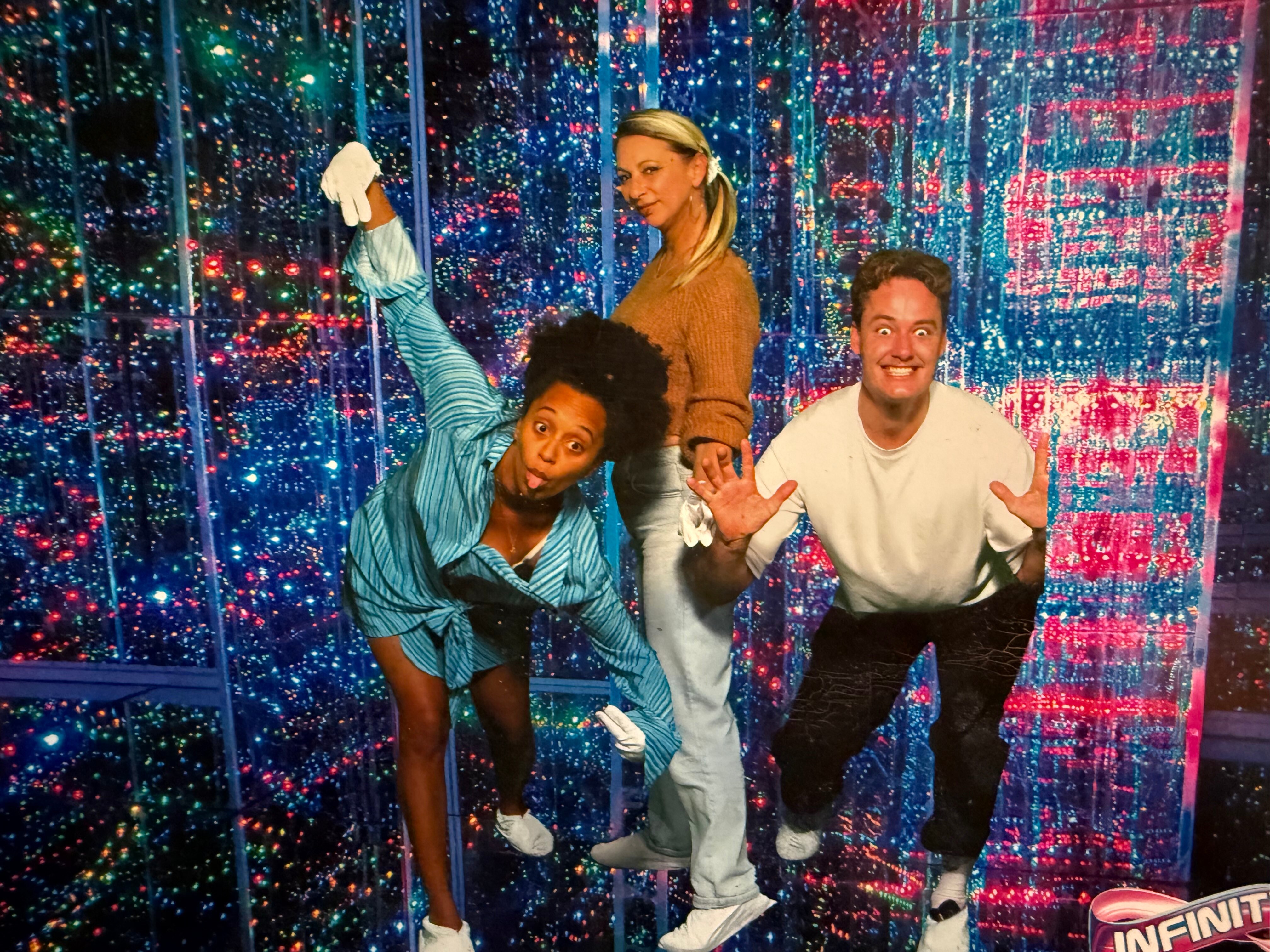 Two women and a man in a light-filled sensory room at a funhouse.