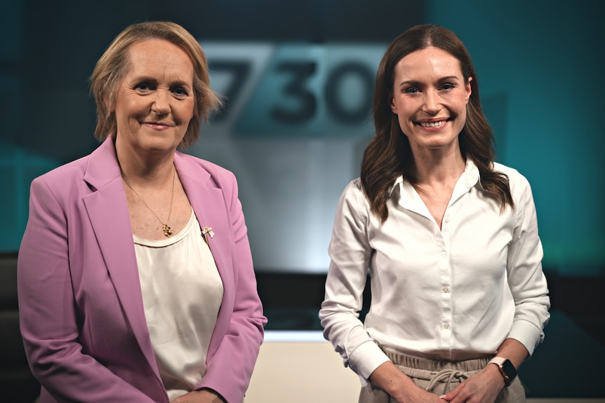 Two women standing in a television studio smiling.