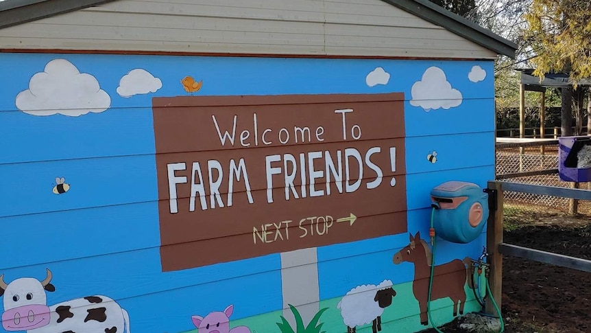 A barn with 'welcome farm friends' on the door.