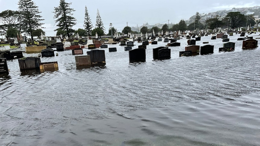 Water laps at dozens of headstones inside the grounds of a cemetery