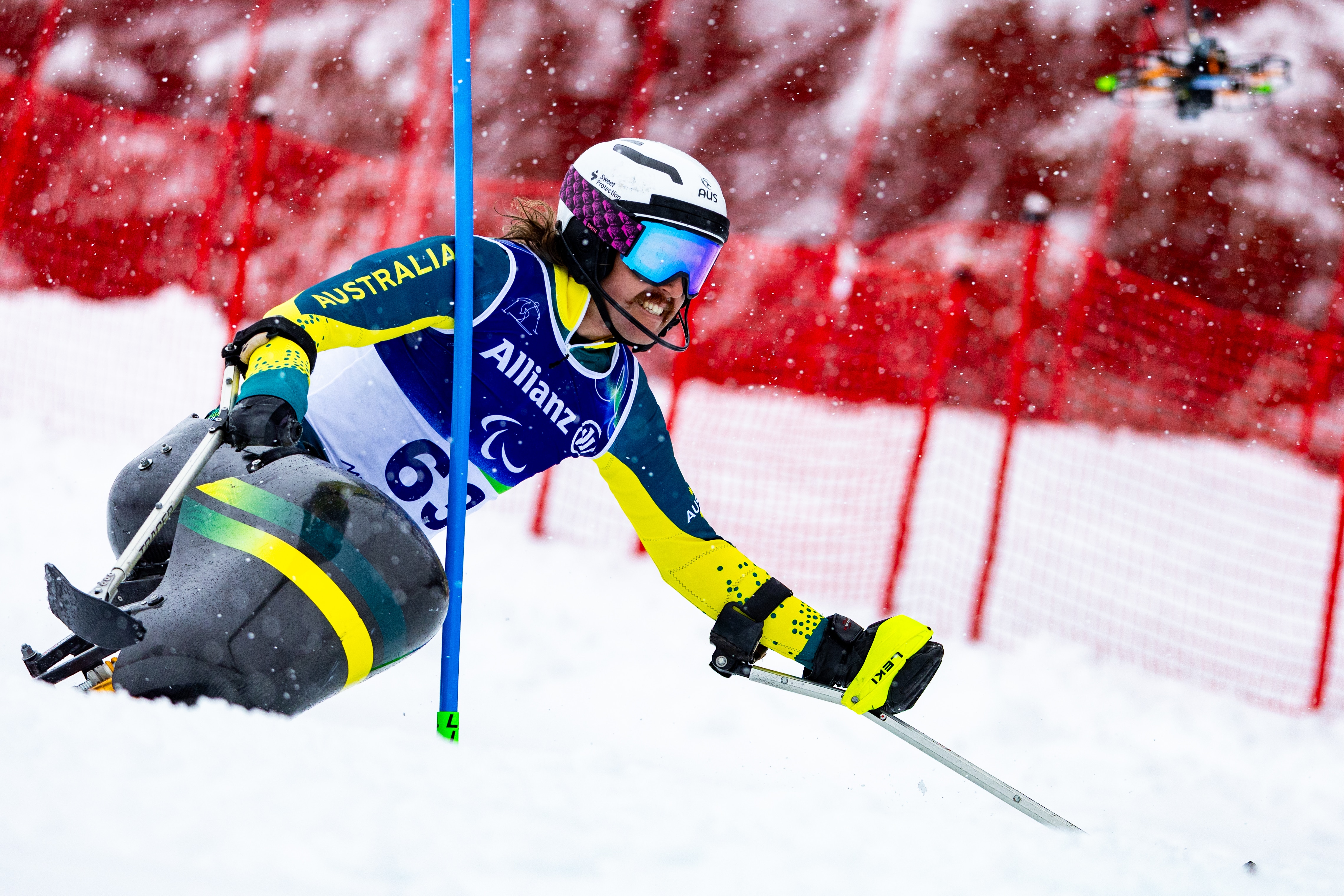 Um esquiador para-alpino australiano manobra em torno de um portão em seu sit-ski durante um evento de slalom das Paraolimpíadas de Inverno.