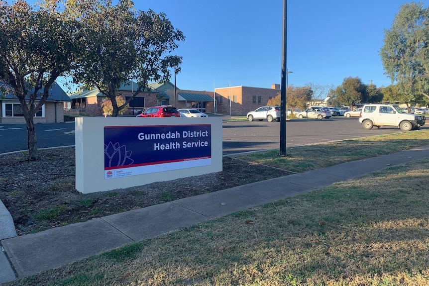 A sign out the front of brick building in the country that reads "Gunnedah Hospital".