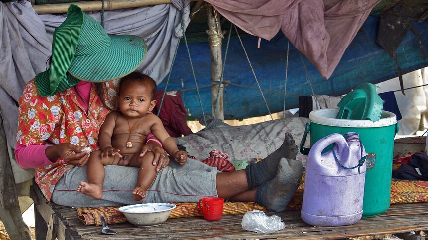 A woman feeds a baby at a Cambodian rubbish dump in Siem Reap