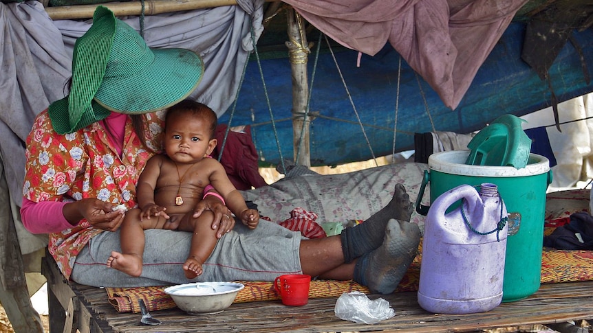 A woman feeds a baby at a Cambodian rubbish dump in Siem Reap