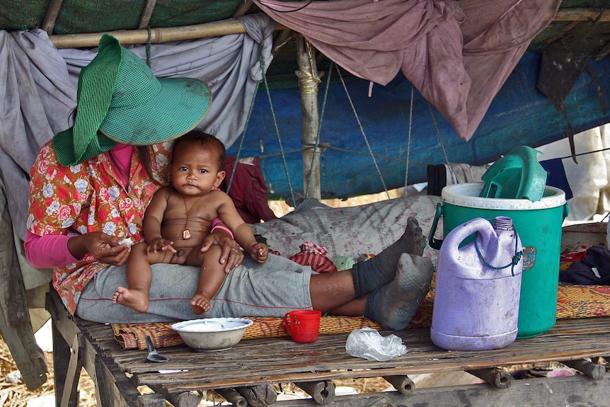 A woman feeds a baby at a Cambodian rubbish dump in Siem Reap