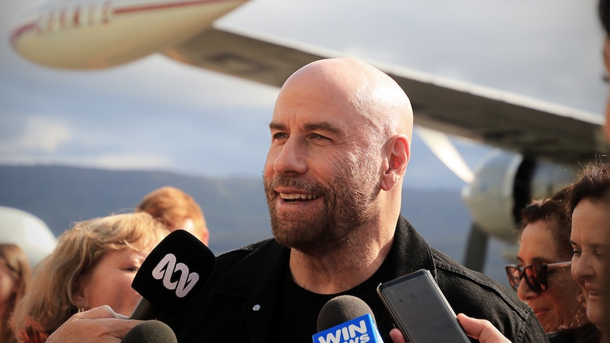 John Travolta talks to media in front of the Connie aircraft at the Shellharbour Airport.